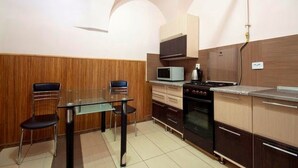 Une cuisine compacte comprenant une table à manger, des chaises, un four à micro-ondes, une cuisinière et des meubles de rangement en bois.
