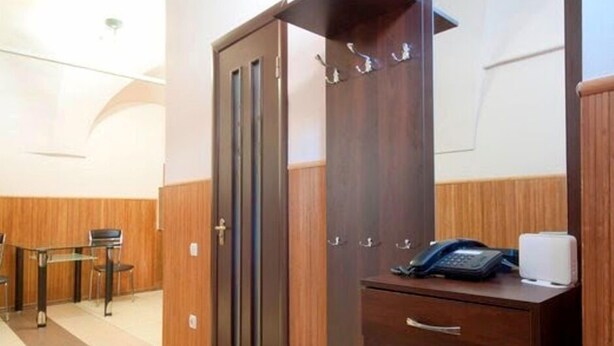 Une chambre d’hôtel avec une armoire en bois, un bureau avec un téléphone et une chaise.
