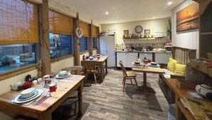 A cozy, well-lit dining area with wooden furniture and a view of the kitchen in the background.