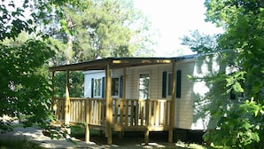 Een klein, gelijkvloers vakantiehuisje met een houten terras en een overdekte veranda.