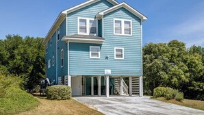 A two-story house with a gabled roof, a covered porch, and a clear driveway. - Bama Breeze | Sound Side | Private Pool, Hot Tub | Kitty Hawk (Kitty Hawk)