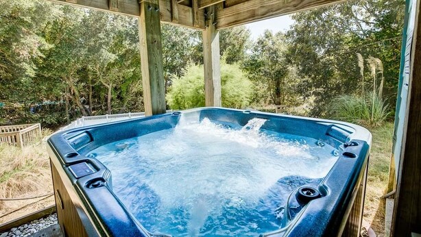 A hot tub with a wooden pergola structure, surrounded by trees and a natural setting. - Bama Breeze | Sound Side | Private Pool, Hot Tub | Kitty Hawk (Kitty Hawk)
