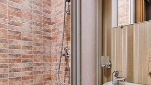 A bathroom with a white bathtub, a shower with a handheld showerhead, and a sink with a mirror above it. - 1 Bedroom Apartment Ave. Svobody 31 (Lviv)