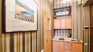 A compact kitchen with striped wallpaper, a framed landscape picture, and wooden cabinets. - 1 Bedroom Apartment Ave. Svobody 31 (Lviv)