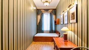 A narrow room with a bed, a desk, and a chair. - 1 Bedroom Apartment Ave. Svobody 31 (Lviv)
