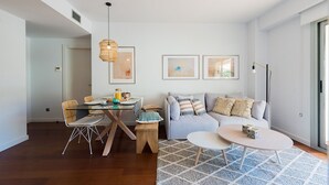A modern living room with a glass dining table, a grey sofa, and a patterned rug. - Petit Luxe Oasi d'Egara (Terrassa)