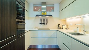A modern kitchen with a built-in oven, a stainless steel sink, and a hanging pot rack. - Petit Luxe Oasi d'Egara (Terrassa)