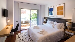 A modern hotel room with a bed, desk, chair, and a sliding door to a balcony. - Petit Luxe Oasi d'Egara (Terrassa)