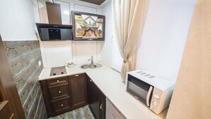 A compact kitchen with a microwave, sink, and cabinets. - 1 Bedroom Apartment Valova 16A (Lviv)