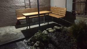 An outdoor seating area with a bench and a table, surrounded by a brick wall and a small rock garden. - 1 Bedroom Apartment Valova 16A (Lviv)