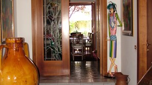 Una habitación con suelo a cuadros, un jarrón grande, una puerta de madera con paneles de vidrio y una estatua.