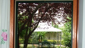 Un comedor con mesa y sillas, vista a un jardín con mesa y sillas, y una puerta que da al exterior.