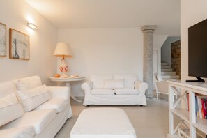 Een moderne woonkamer met een witte bank, een kleine ronde tafel met een lamp en een boekenkast.