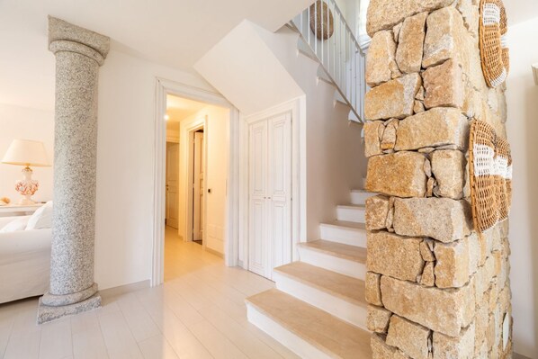 A staircase with stone steps and a column, leading to a room with a white door.