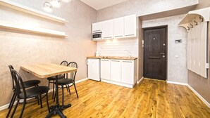 A compact kitchen with white cabinets, a microwave, and a dark wooden door. - Apartment Mitskevicha 5a (Lviv)