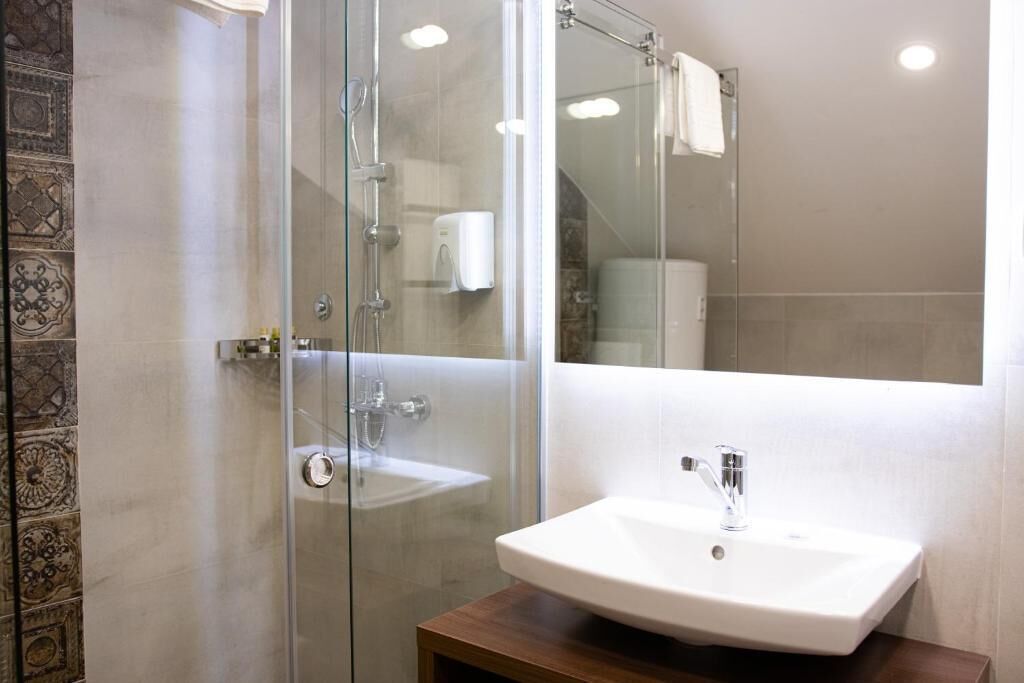 Un baño con cabina de ducha de vidrio, un lavamanos blanco y un espejo.