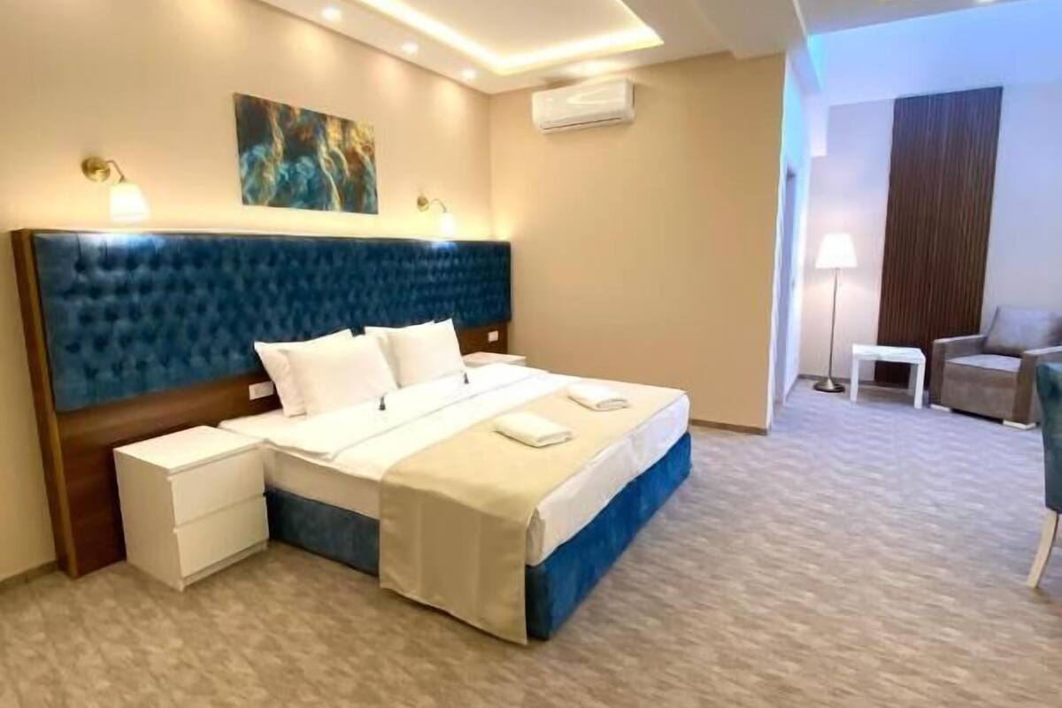 Una habitación de hotel con una cama grande, mesitas de noche, un escritorio y una silla.