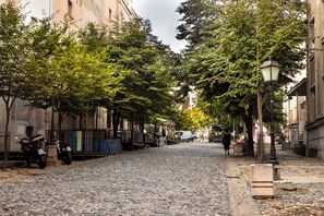 Une rue pavée bordée d’arbres et où sont garées des motos.