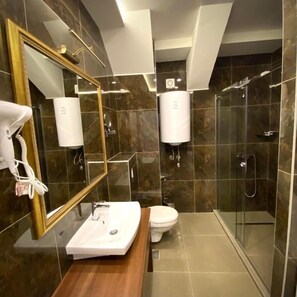 Une salle de bain moderne avec un grand miroir, un lavabo, des toilettes et une douche à parois de verre.