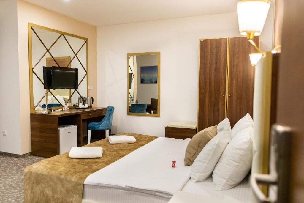 A hotel room with a bed, a desk, a chair, a television, and a wardrobe.