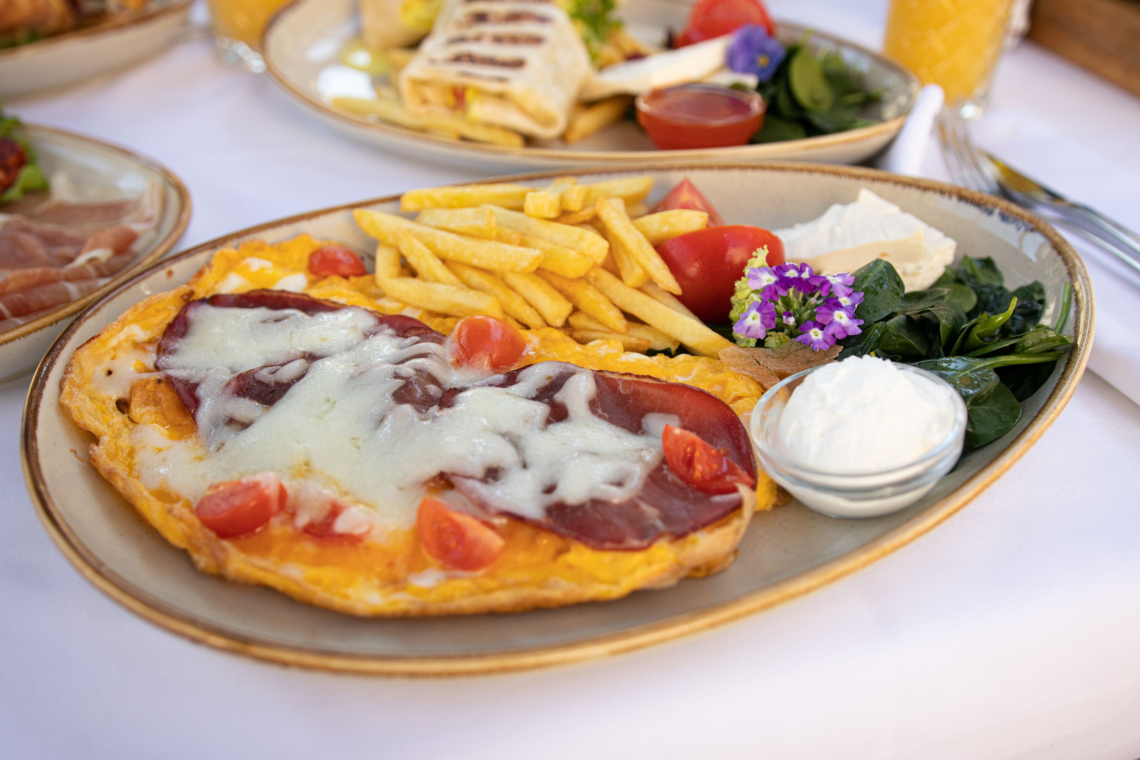 Un plato con un desayuno que incluye huevos, queso, tomates y una porción de papas fritas.