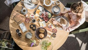 A round wooden table with a variety of breakfast items including bread, meats, cheeses, and fruits. - Genusswerk Eifel - Boutique Hotel (Korperich)