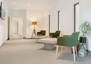 Un interior moderno con un sofá, sillones, una lámpara de pie y una planta en maceta.