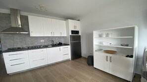A modern kitchen with white cabinets, a stainless steel refrigerator, and a microwave.