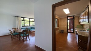 A spacious living area with a dining table and chairs, a built-in bench, and a view through a window.