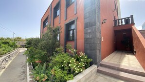 A building with a red facade, a stone pillar, and a small balcony.