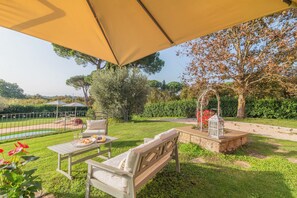Relax and dine in a serene outdoor setting with a well-maintained lawn, dining table, and comfortable seating.