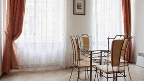 Un comedor con una mesa de vidrio y sillas de metal, un cuadro en la pared y cortinas traslúcidas.
