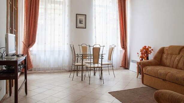 Una sala de estar con una mesa de comedor y sillas, un sofá y un televisor sobre un mueble.