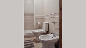 Un baño con inodoro, bidé y lavamanos.