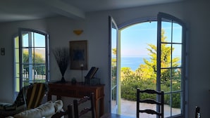 A dining area with a view of the sea, a table, chairs, a sofa, and a decorative vase. - In Saint Florent, villa with panoramic gulf view and private pool (Sain-Florent)