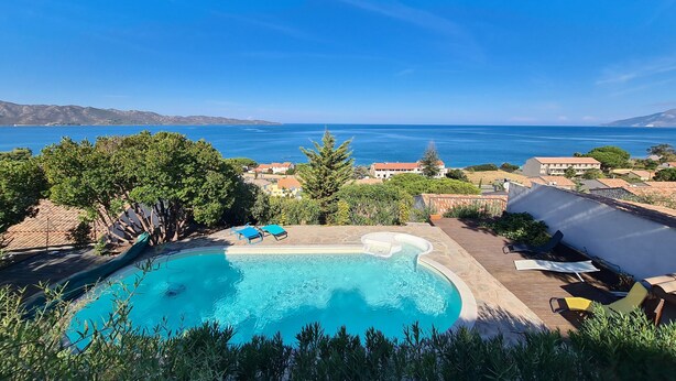 A swimming pool with a hot tub, surrounded by greenery and overlooking a coastal view. - In Saint Florent, villa with panoramic gulf view and private pool (Sain-Florent)