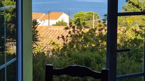 A view from a room with a large window overlooking a coastal area, including a body of water and distant land. - In Saint Florent, villa with panoramic gulf view and private pool (Sain-Florent)