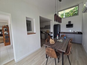 A modern kitchen with a dining area, a built-in oven, and a window with a view of greenery. - In Saint Florent, villa with panoramic gulf view and private pool (Sain-Florent)