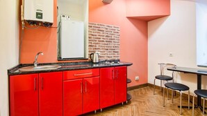 A kitchen with red cabinets, a sink, a stove, and a brick wall. - Apartment Kostushka 5 (Lviv)