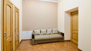 A room with a beige sofa, wooden doors, and a radiator. - Apartment Kostushka 5 (Lviv)