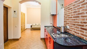 A modern kitchen with a brick backsplash, wooden flooring, and a built-in oven. - Apartment Kostushka 5 (Lviv)