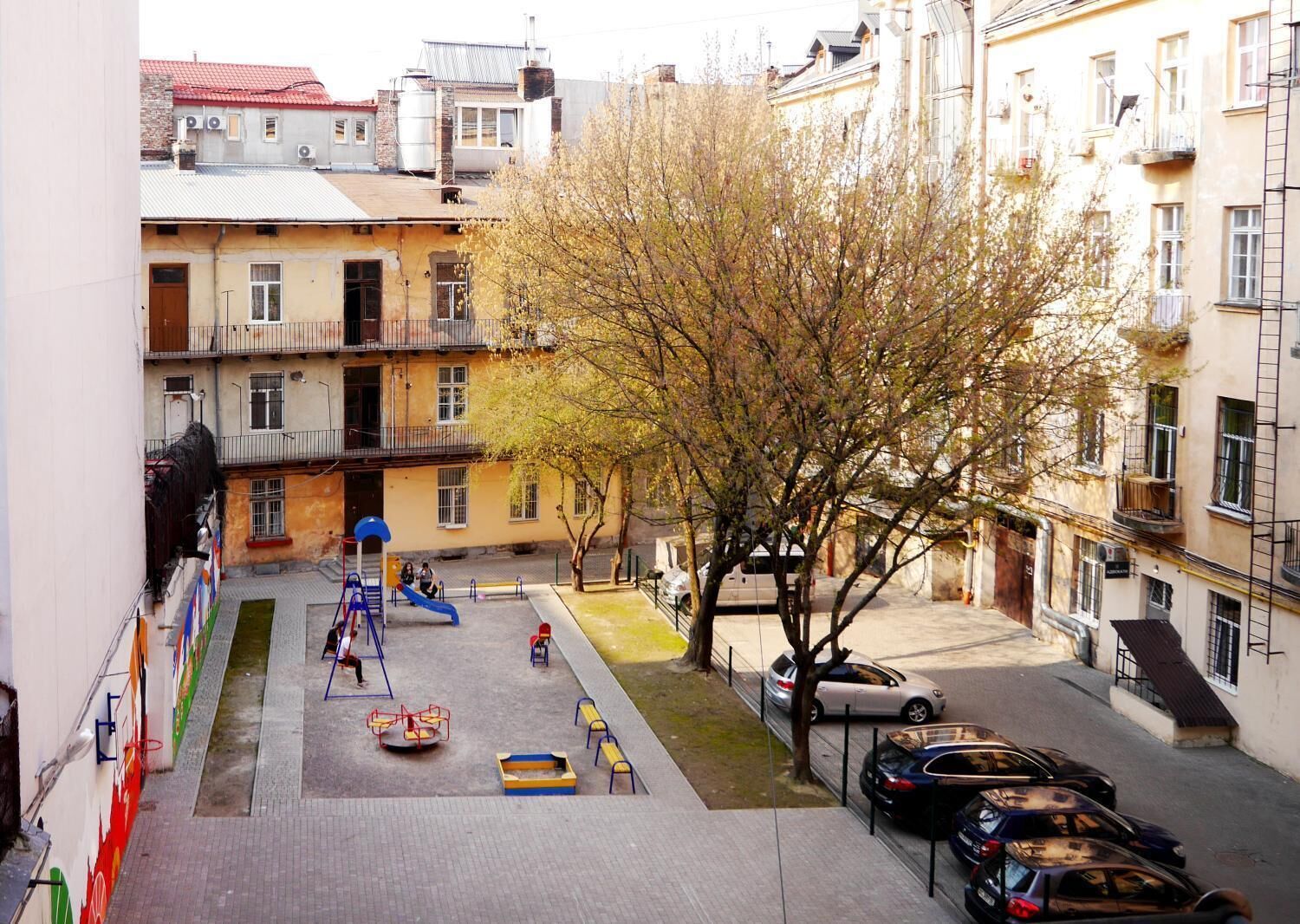 A courtyard with a playground, parked cars, and residential buildings.