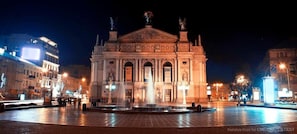 Un edificio histórico con arquitectura clásica, una fuente central y entorno iluminado.
