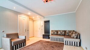 Una sala moderna con alfombra marrón, un sofá con cojines estampados y una mesita auxiliar.