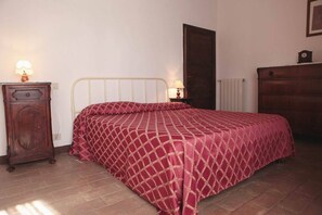 A bedroom with a bed, a dresser, a nightstand, and a lamp.