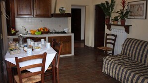 Una cocina con armarios de madera, una mesa de comedor con sillas, un sofá y plantas en macetas.