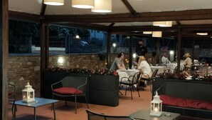 An outdoor dining area with stone walls, tables, chairs, and lanterns. - Locanda Giustini (Assisi)
