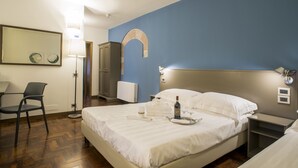A hotel room with a bed, a chair, a desk, a lamp, and a wall-mounted mirror. - Locanda Giustini (Assisi)