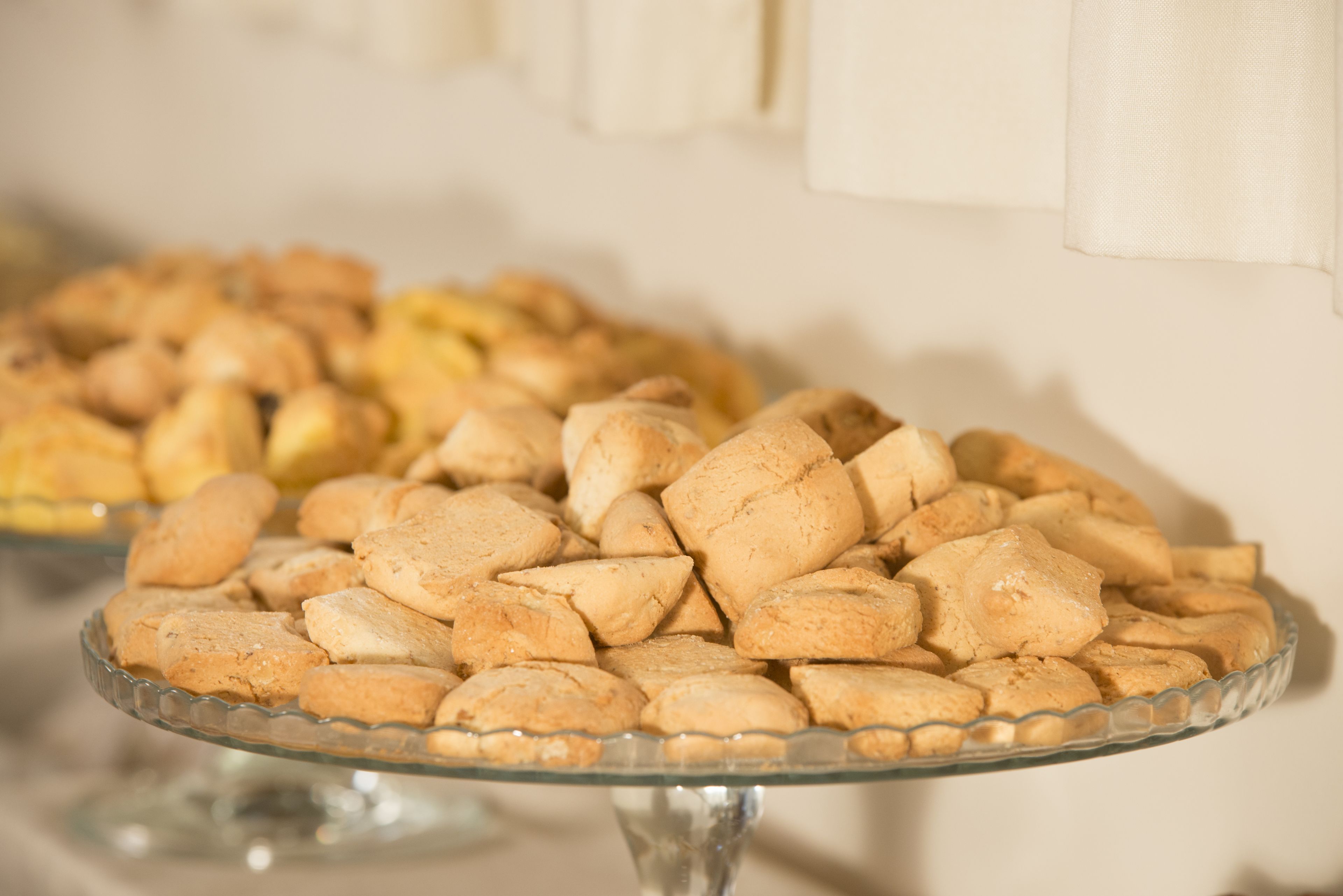 Un recipiente de vidrio lleno de pasteles redondos y dorados sobre una mesa.