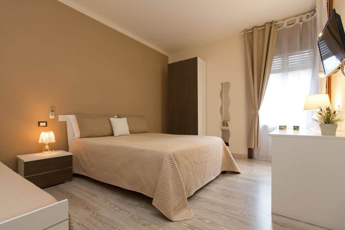 Une chambre d’hôtel avec un lit, une table de chevet, une lampe et un téléviseur posé sur un meuble.